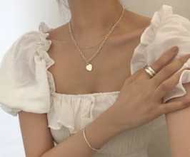 gold necklace and a white milkmaid top with puffy sleeves
